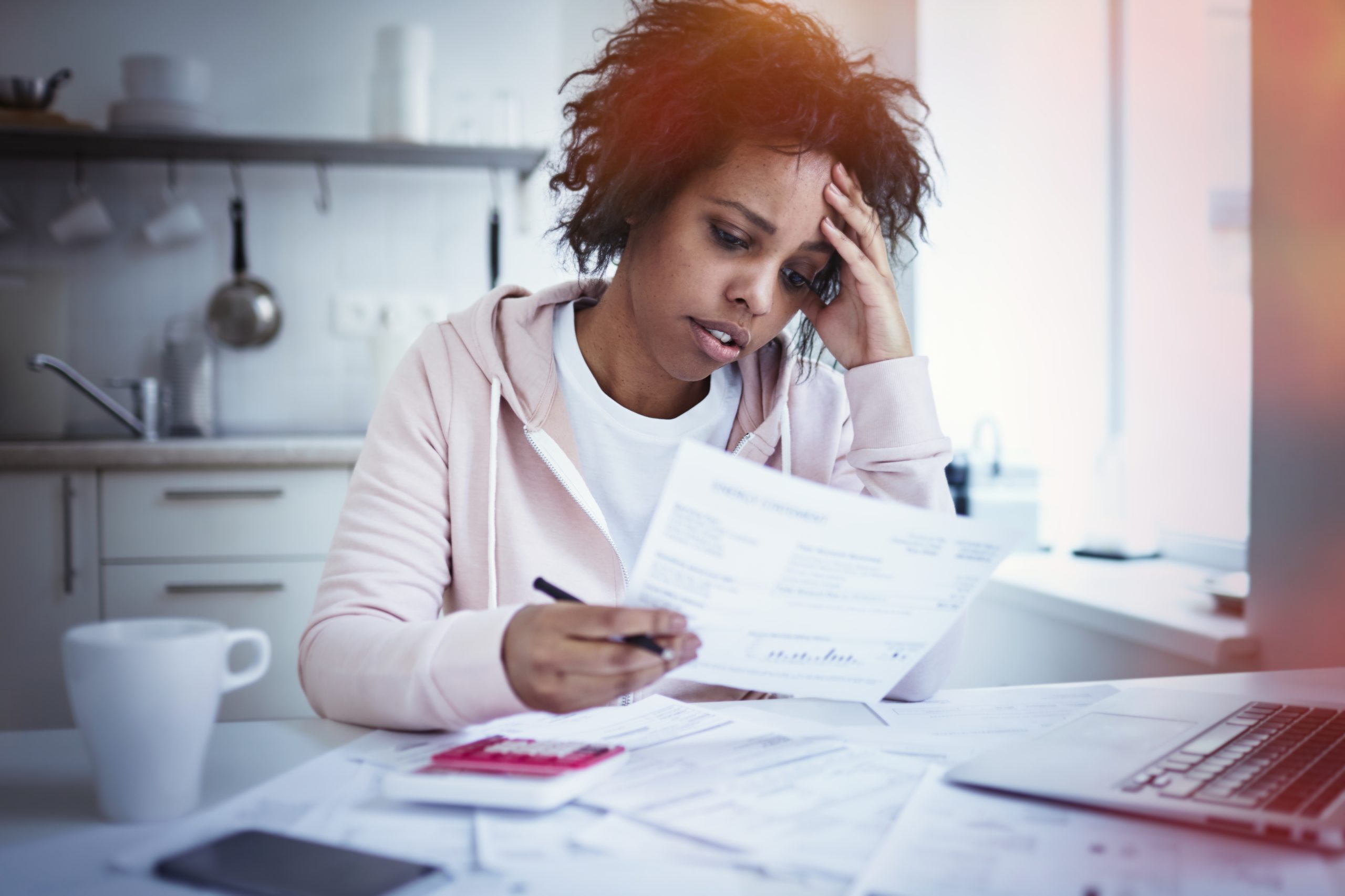 Young upset african american female sitting at kitchen table with laptop dealing with financial stress feeling pressure because of mortgage debt worrying a lot or feeling anxious over money
