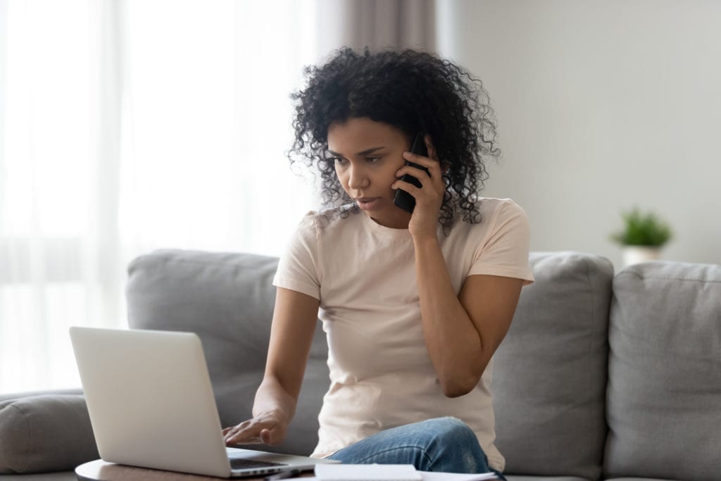 African American Woman talking on the phone while searching on her computer